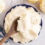 Large bowl of Italian Meringue Buttercream frosting with a wooden spoon in the bowl.