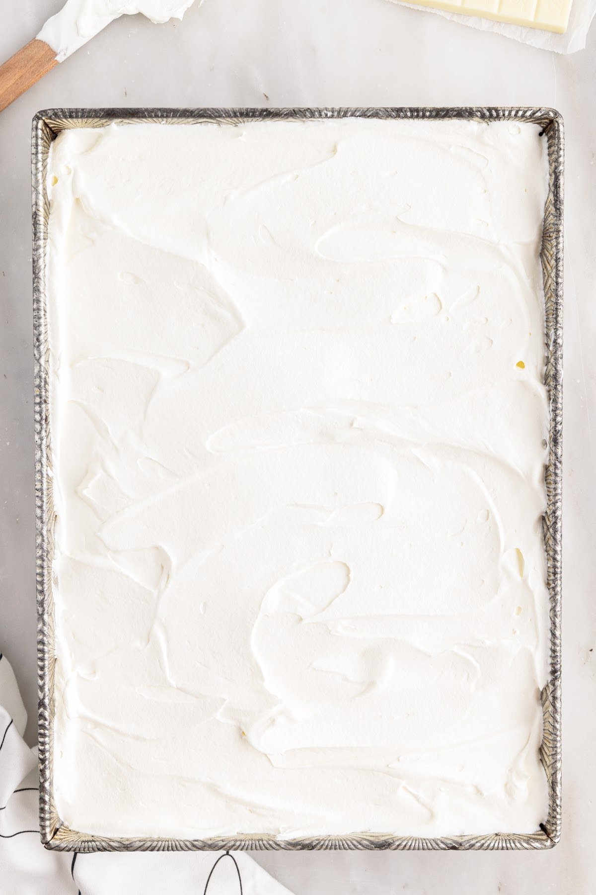 Lasagna topped with cool whip in the baking dish.