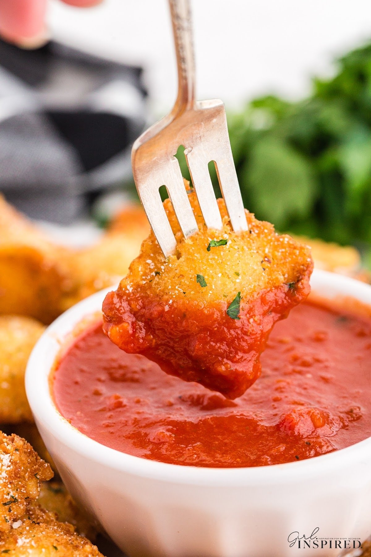 Fried Ravioli on a fork being dipped into the marinara sauce.