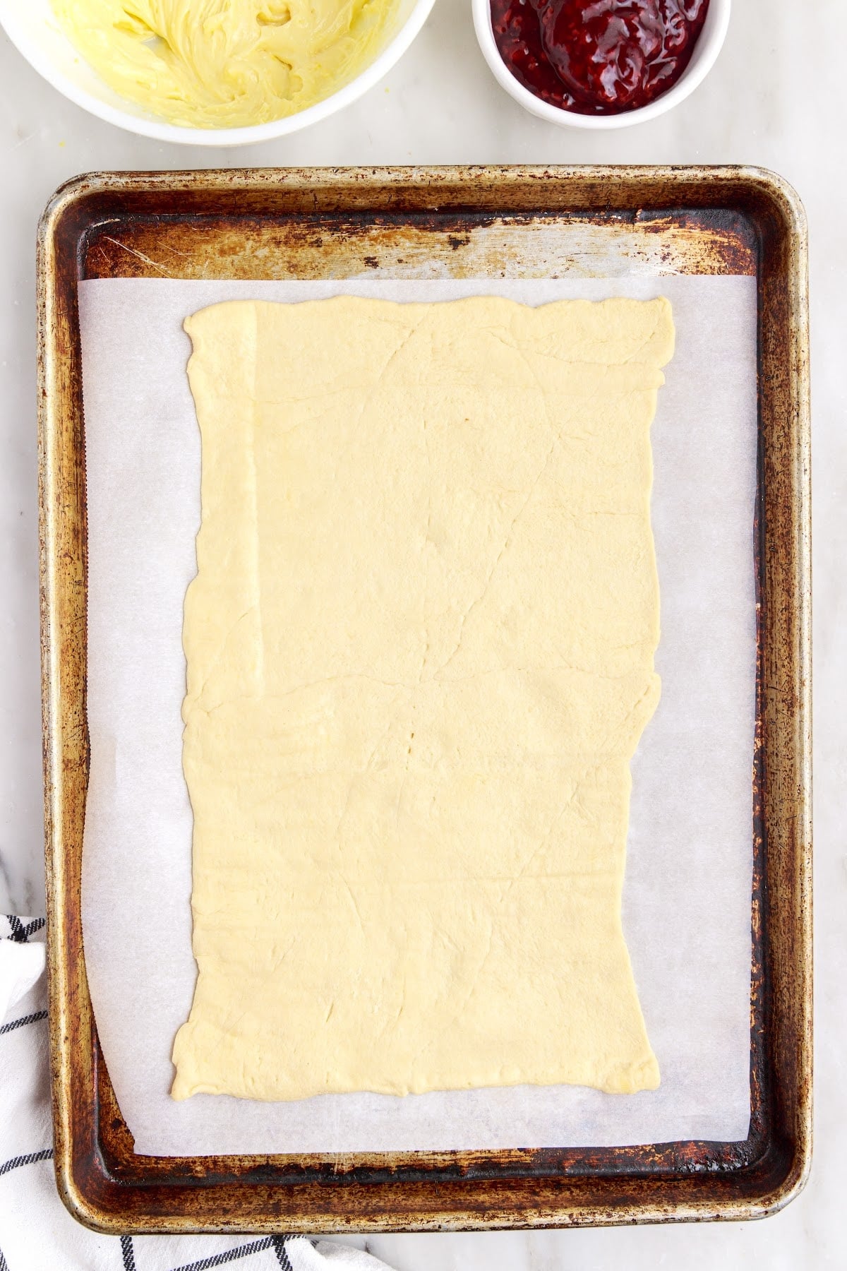 Unrolled crescent roll dough on a cooking sheet.