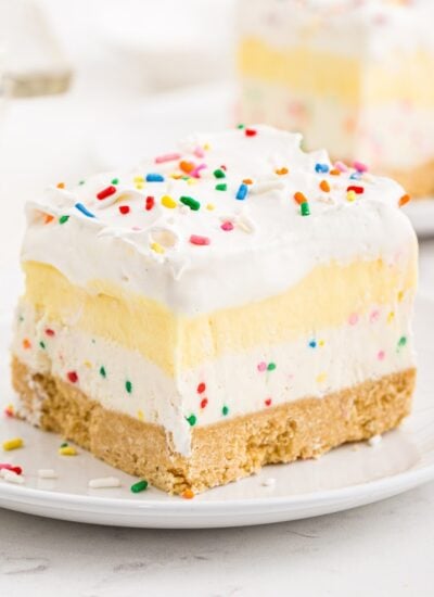 Large slices of birthday cake cheesecake bars showing the layers, with text overlay.