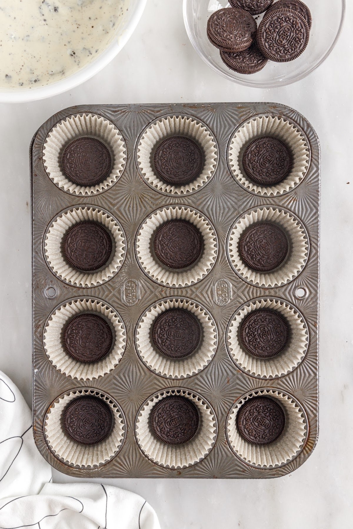 Muffin Pan lined with cupcake liners and an Oreo in the center of each one.