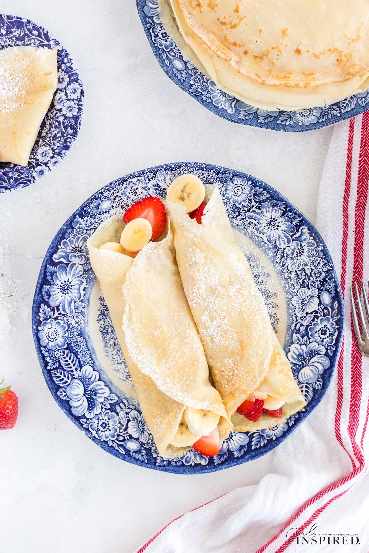 Two stuffed breakfast crepes on a blue floral plate.