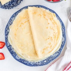 A stack of fresh breakfast crepes on a blue plate.