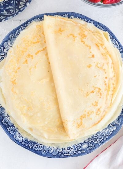 A stack of fresh breakfast crepes on a blue plate.