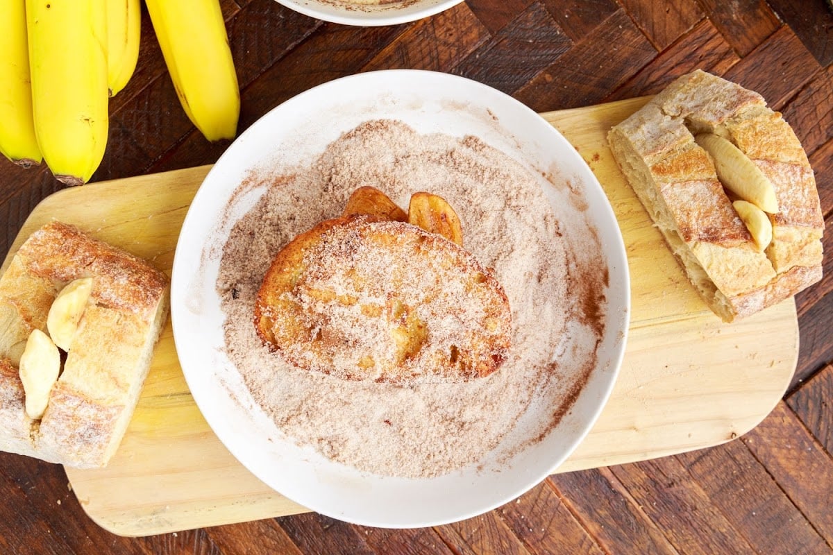 Dipping the fried bread into the cinnamon and sugar mixture.