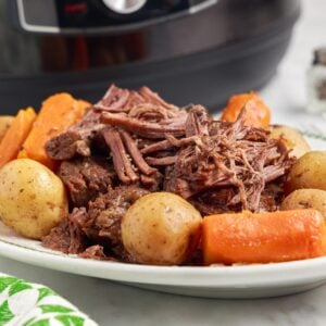 Instant Pot Pot Roast on a platter to serve with veggies surrounding the roast.