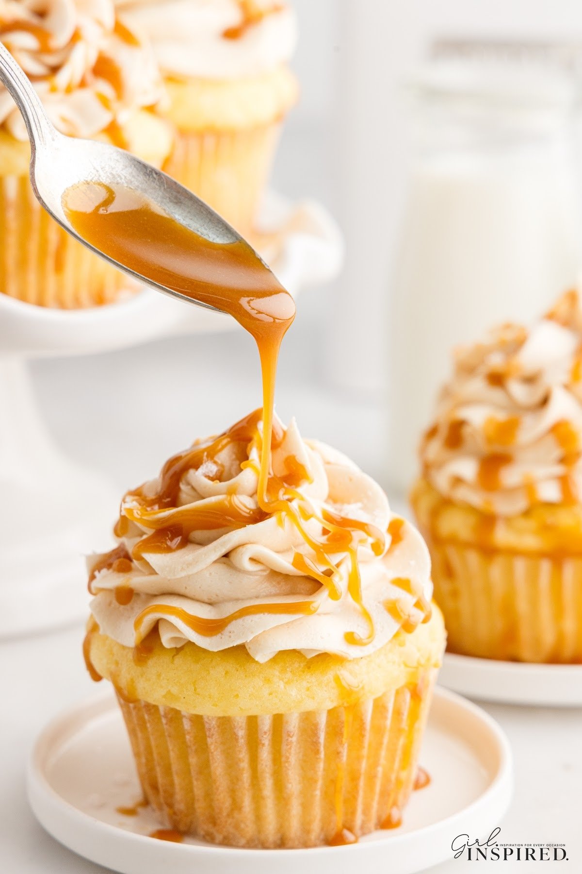 Salted Caramel Cupcakes on a plate, drizzled with caramel.