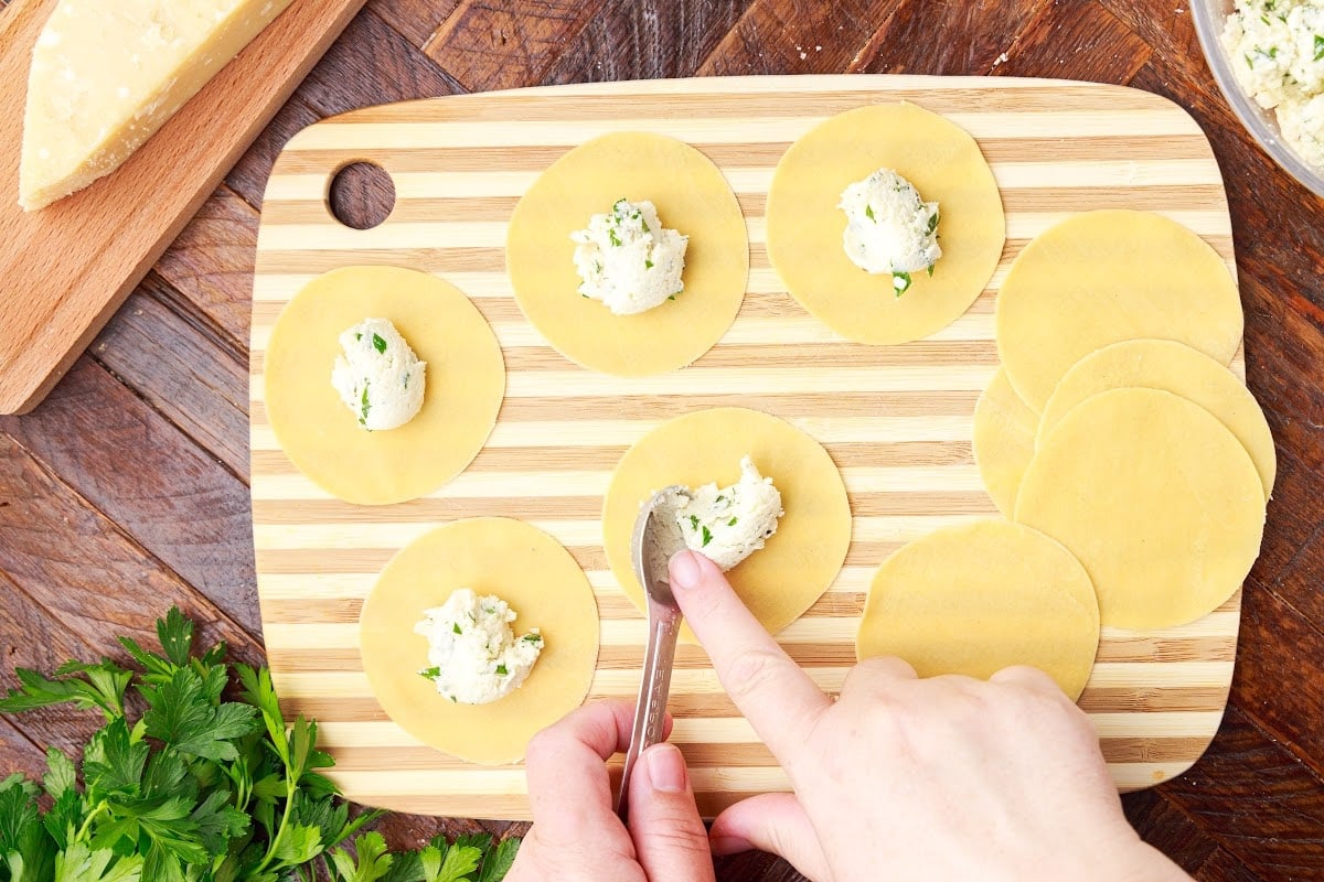 A spoonful of cheese filling placed on each dough round.