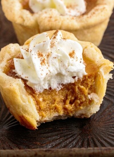 Close up of a little pumpkin pie bite, with a bite taken out of it.