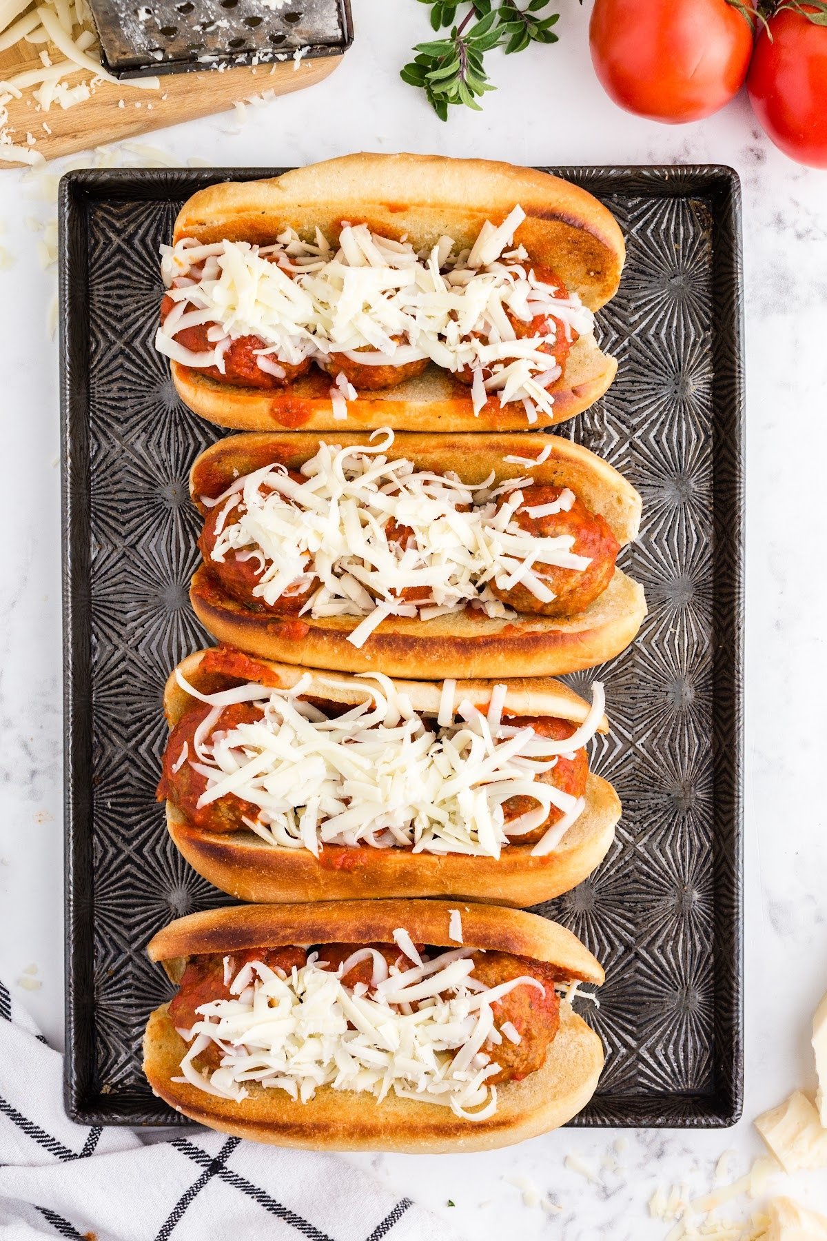 Topping each sub with cheese.