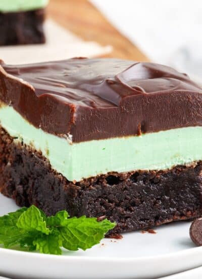 A mint chocolate brownie on a small plate garnished with a mint leaf.