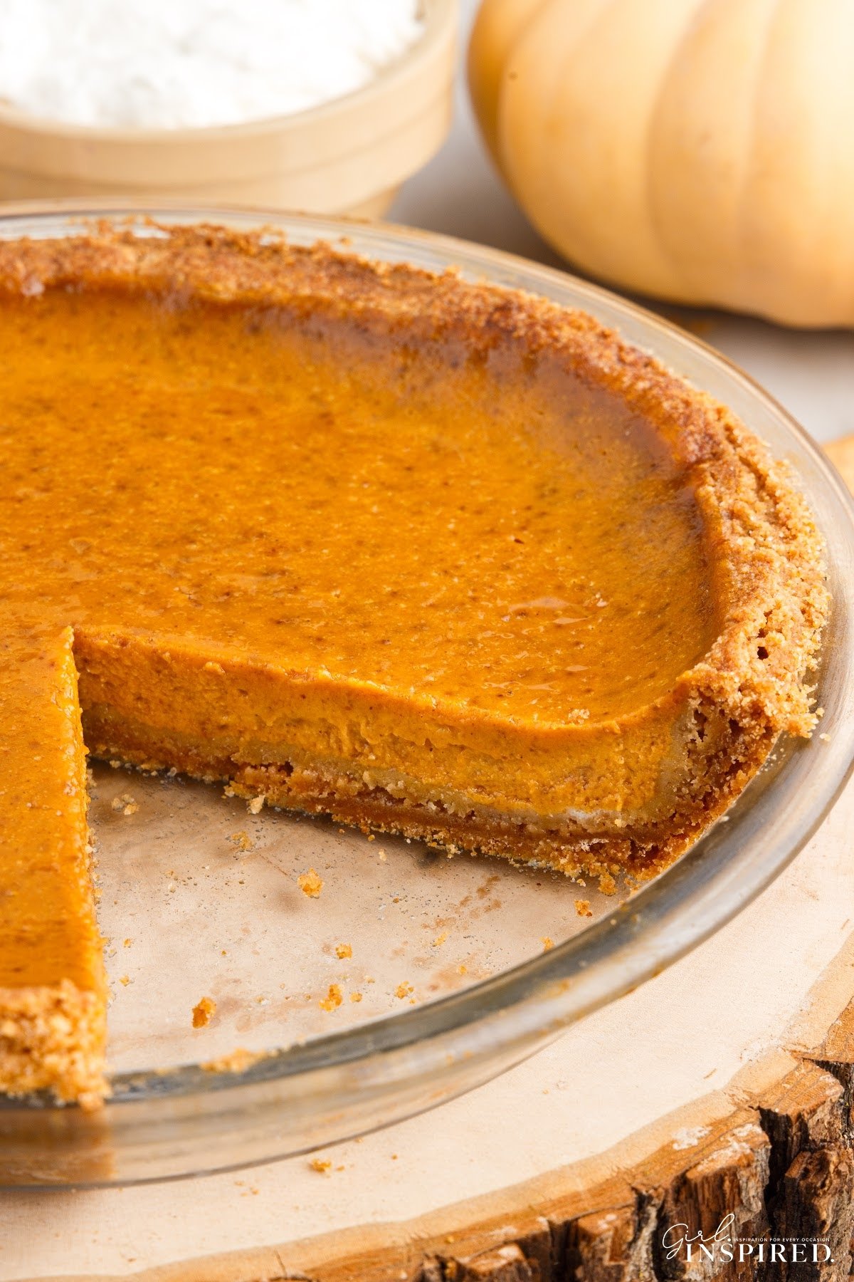 A fresh baked pumpkin pie with a graham cracker crust with a slice missing.