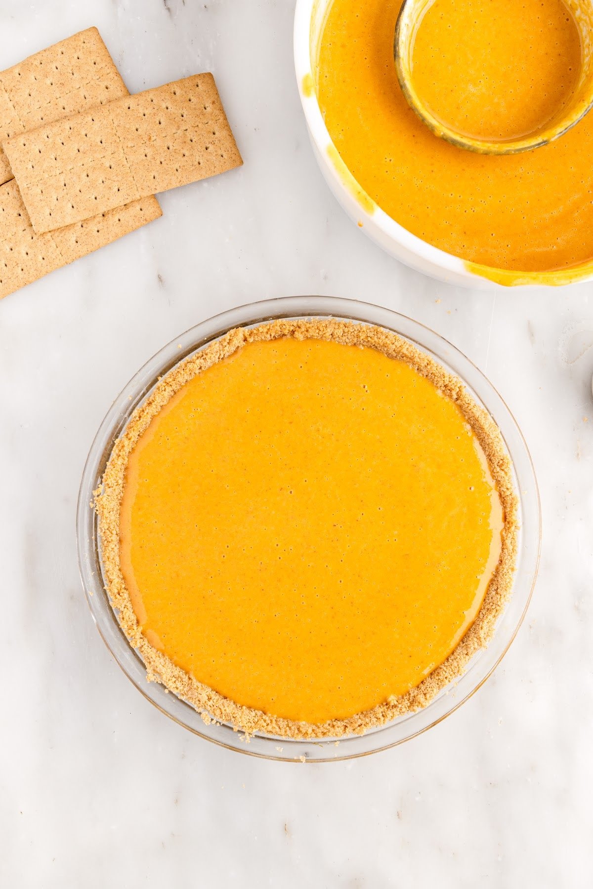 Pumpkin pie filling in the graham cracker crust before baking.