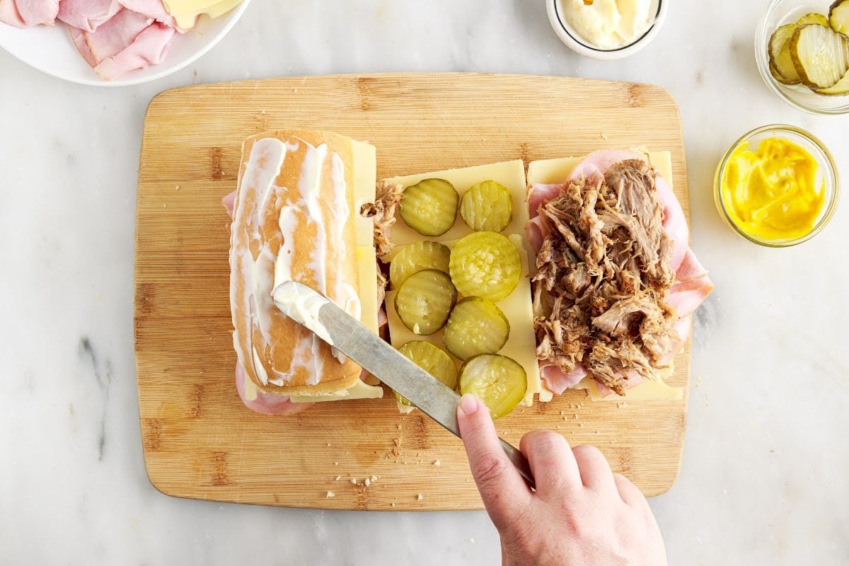 Spreading mayonnaise on the top of each bread piece.