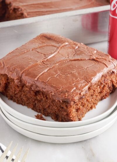 Slice of Coca Cola Cake on a plate, with a can of Coke behind it.