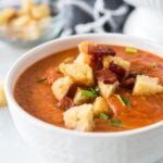 close up of a bowl of Tomato Basil Bisque with croutons and toppings.