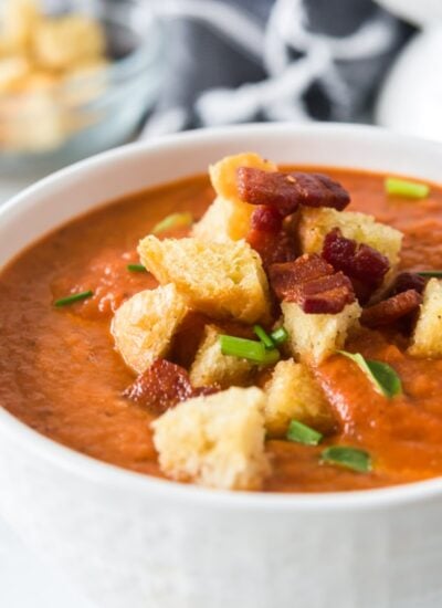 close up of a bowl of Tomato Basil Bisque with croutons and toppings.