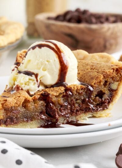 A slice of Chocolate Chip Pie, with ice cream and drizzled chocolate on top.