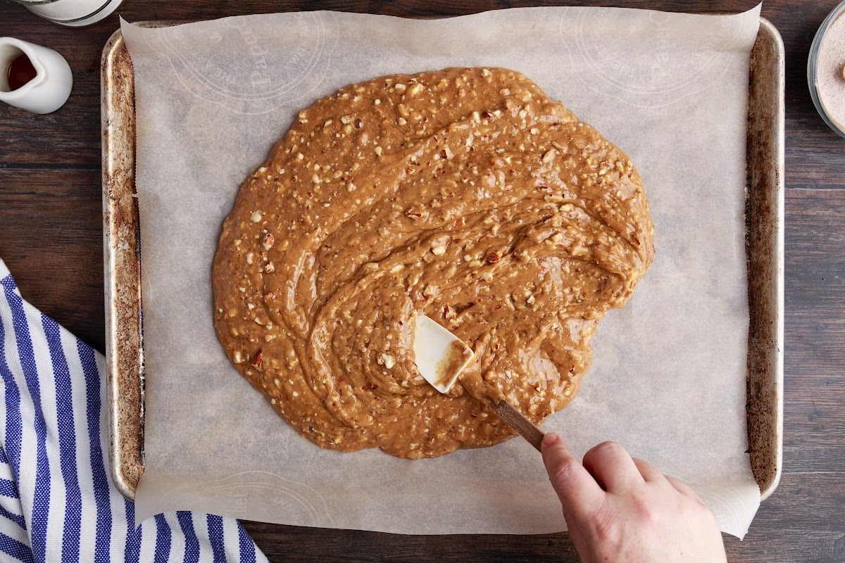 Spreading the toffee mixture on the prepared baking sheet.