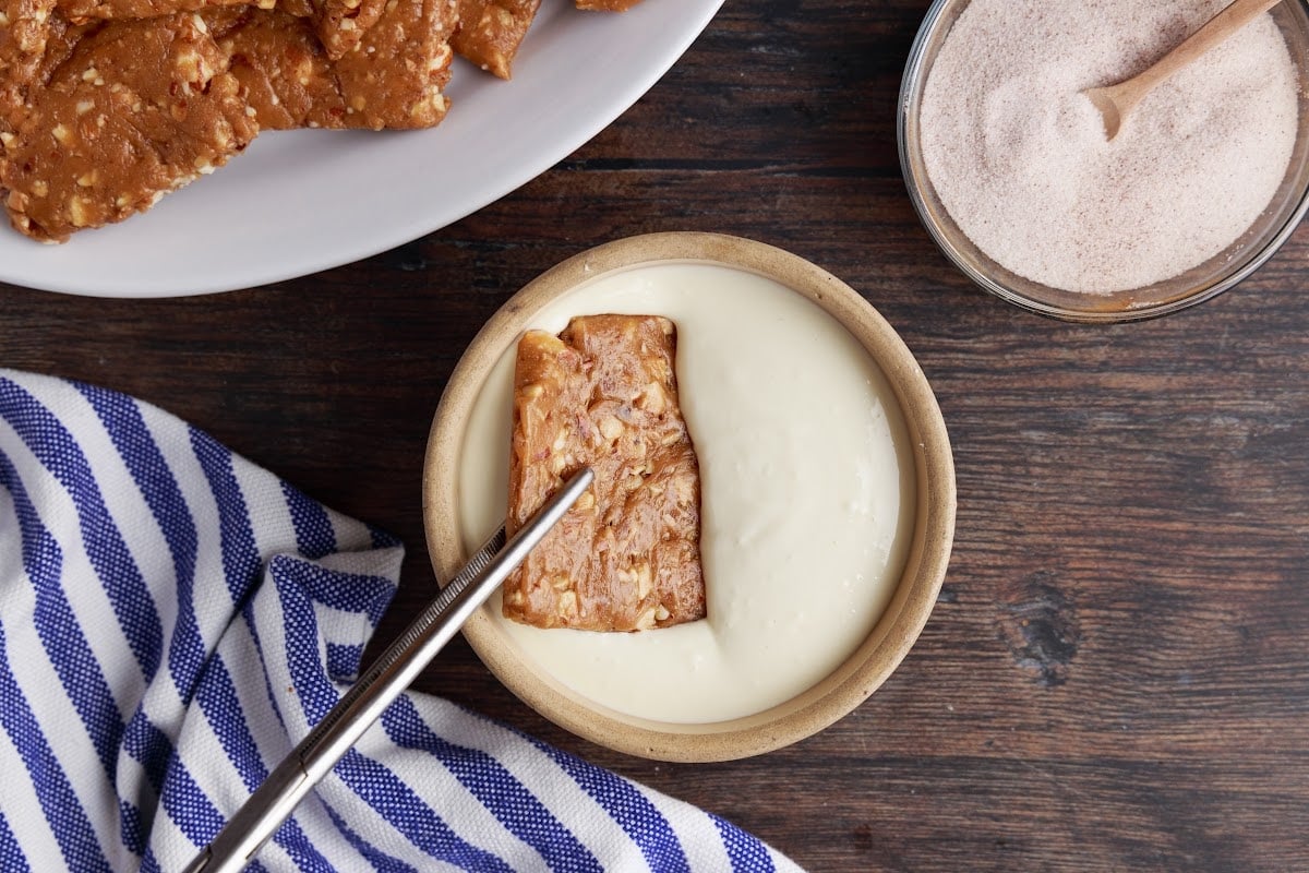 Dipping the toffee squares into the melted chocolate.