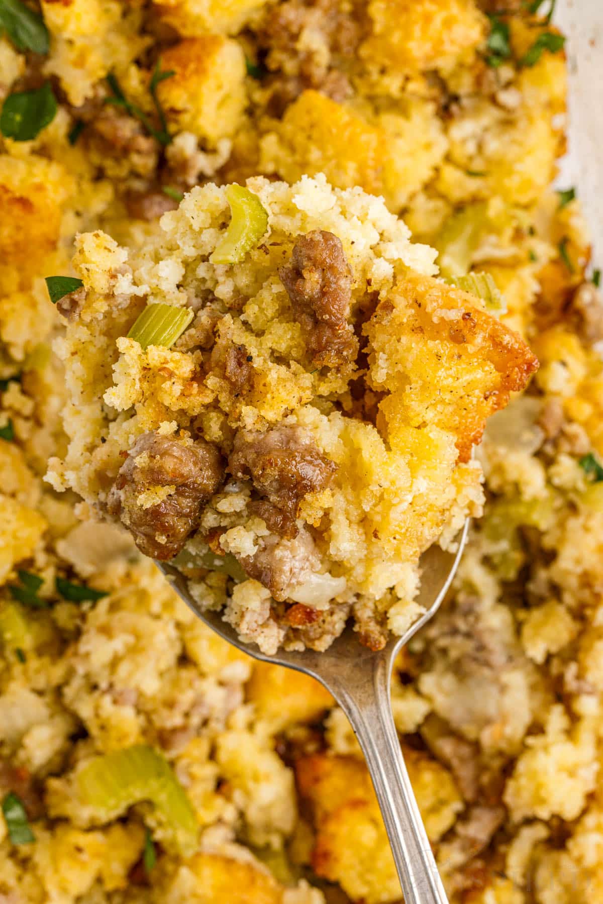 Close up of a spoon filled with Cornbread Sausage Stuffing.