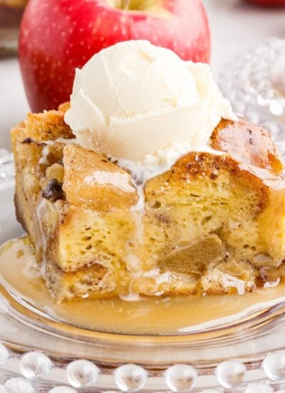 Slice of Apple Bread Pudding on a plate with ice cream on top.