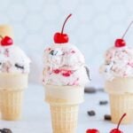 Three cones of cherry garcia ice cream with cherries on top.