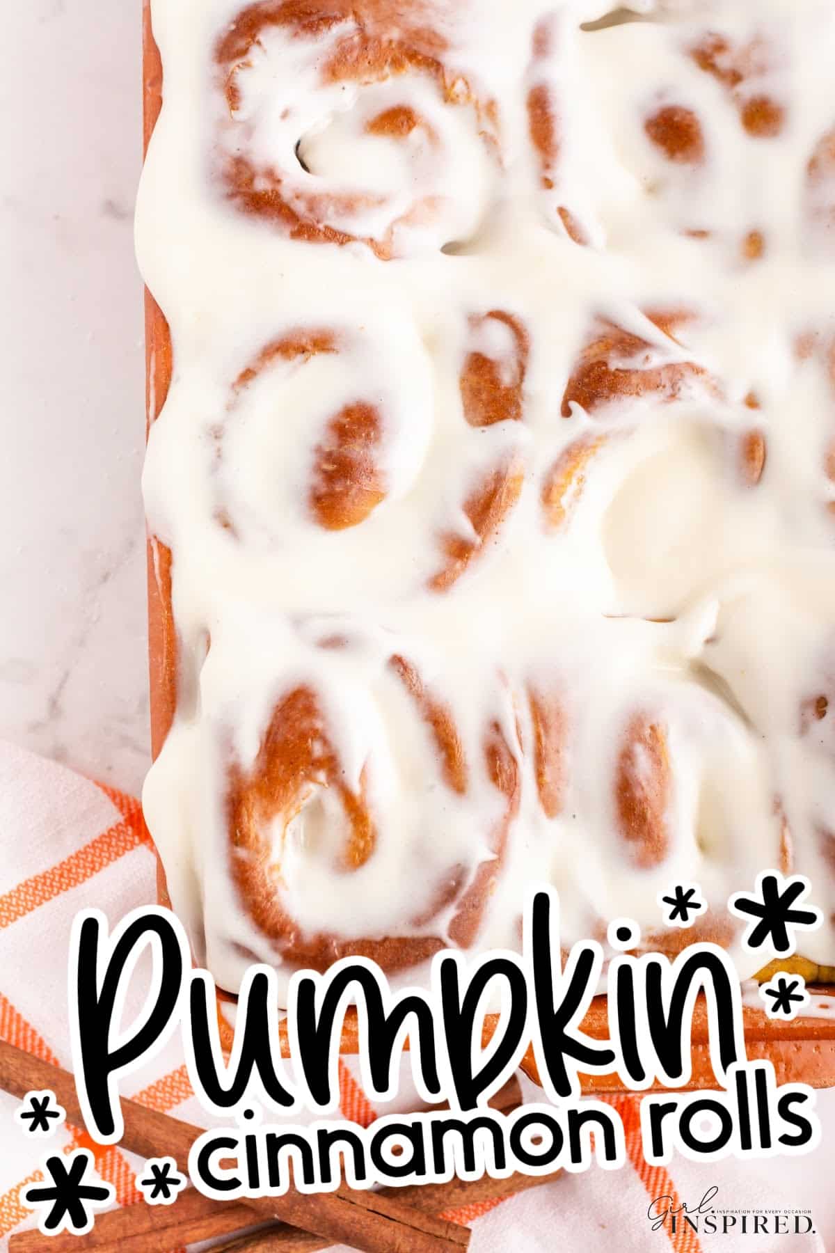 Top view of Pumpkin Spice Cinnamon Rolls with frosting and text overlay.