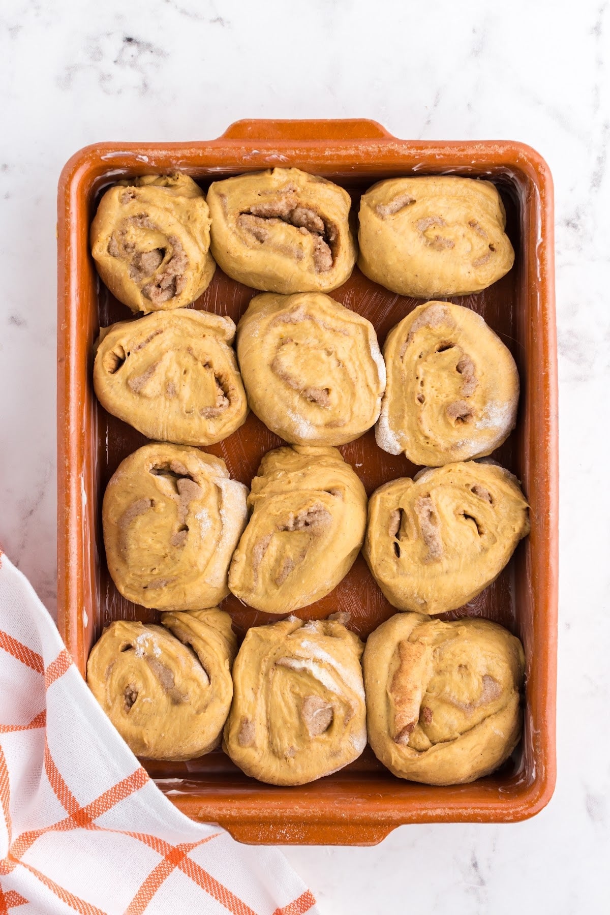 Cinnamon rolls in a baking dish setting to raise.