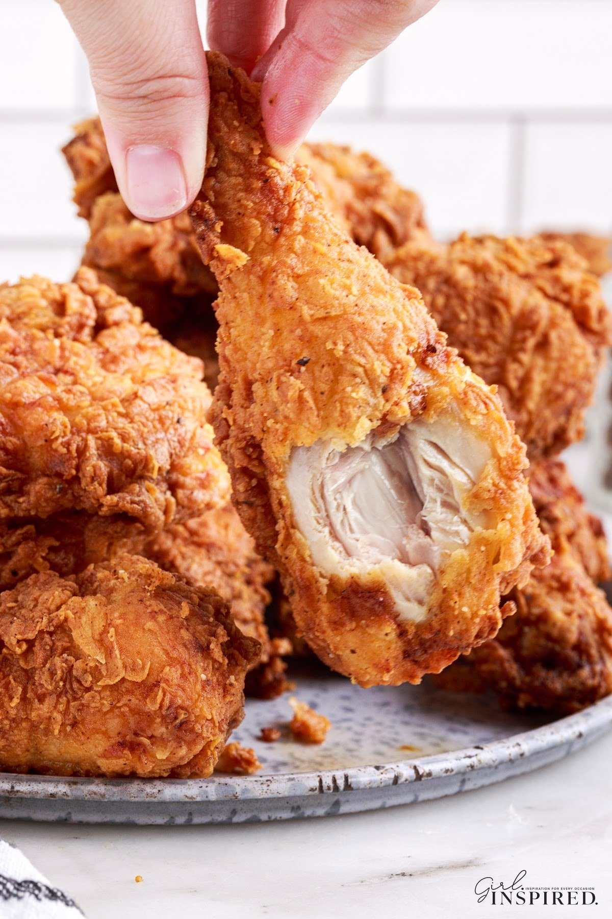 Plate of Southern Fried Chicken and a drum stick with a bite taken out of it.