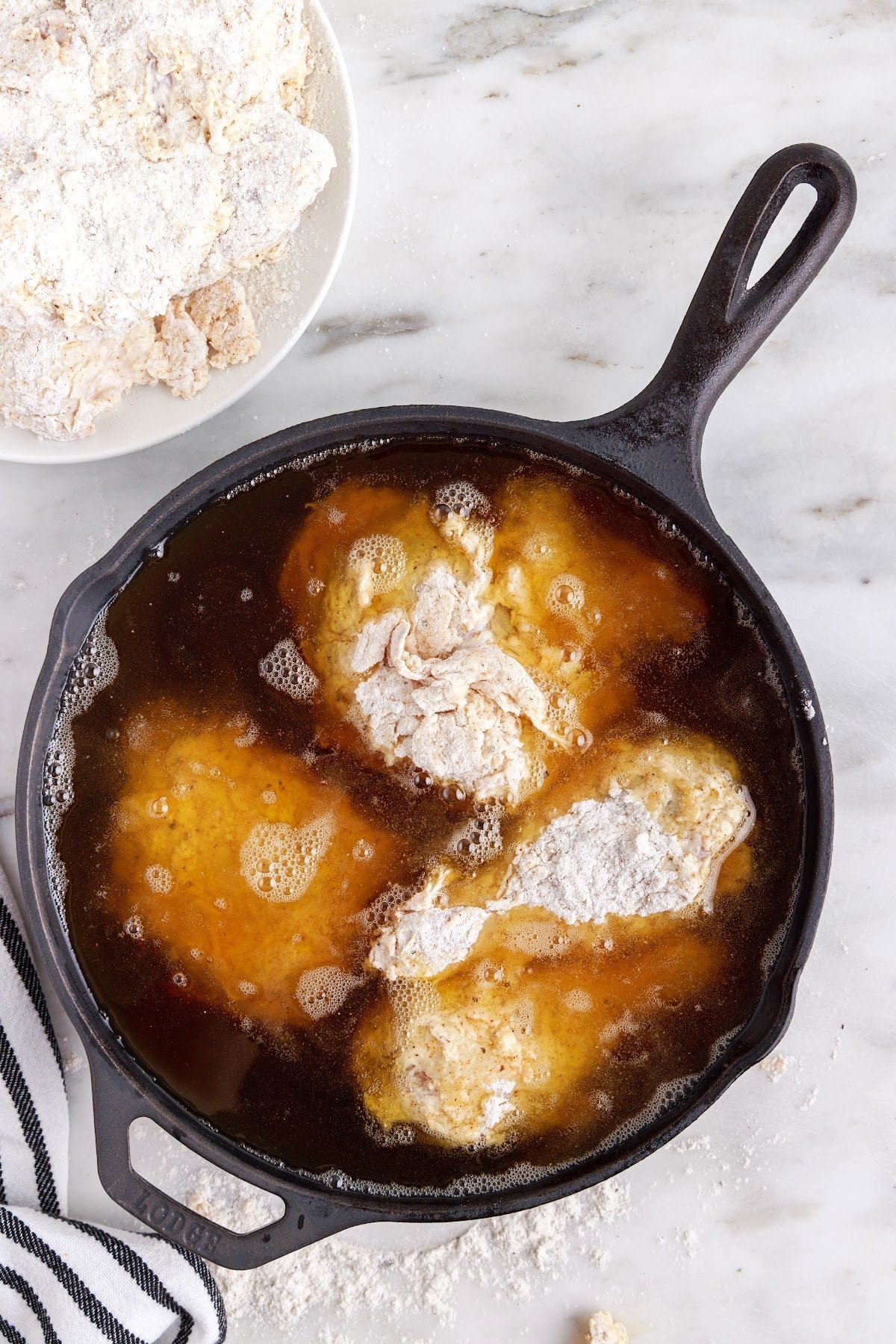 Submerge the coated chicken into the hot oil to fry.