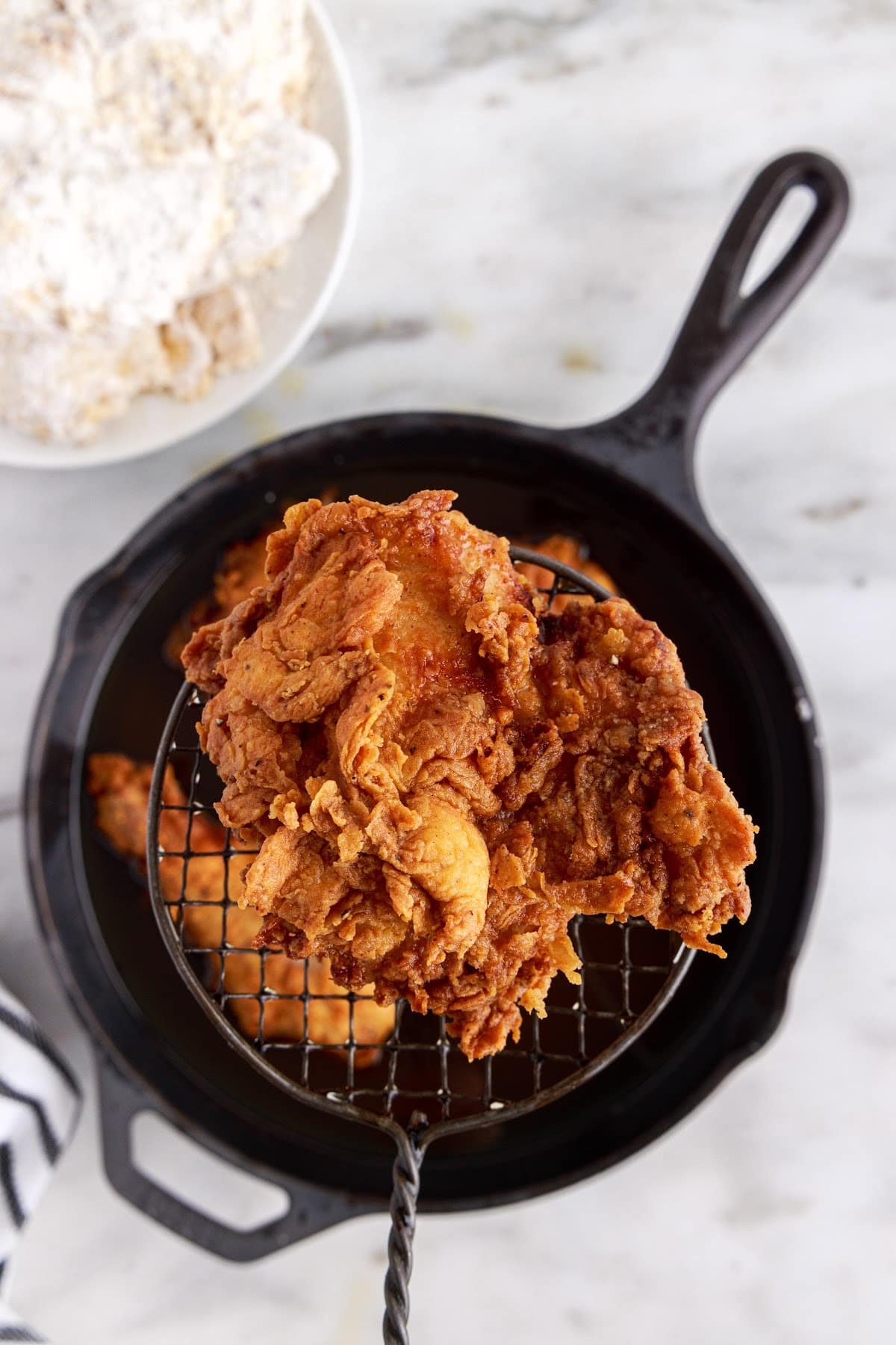 Cooling the fried chicken in the pan, outside of the oil.