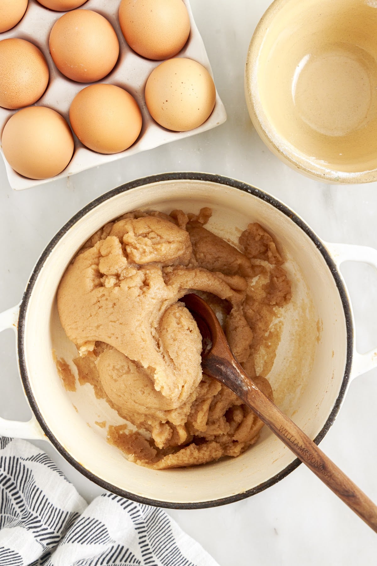 Put the pan on the stove to mix and cook ingredients, with eggs and a bowl off to the side.