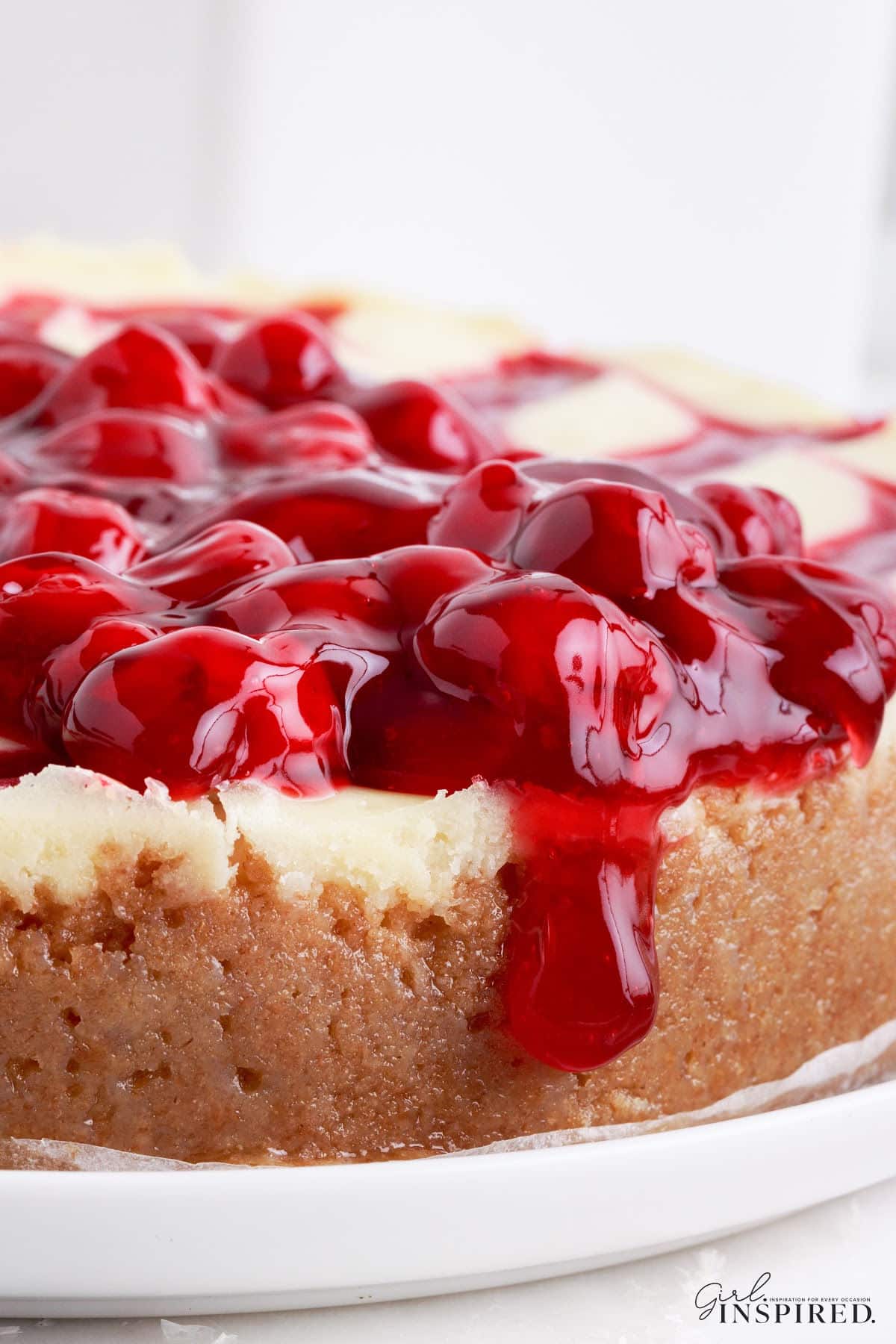 Side view of the Cherry Cheesecake showing the graham cracker crust, cheesecake filling and cherries oozing over the side.