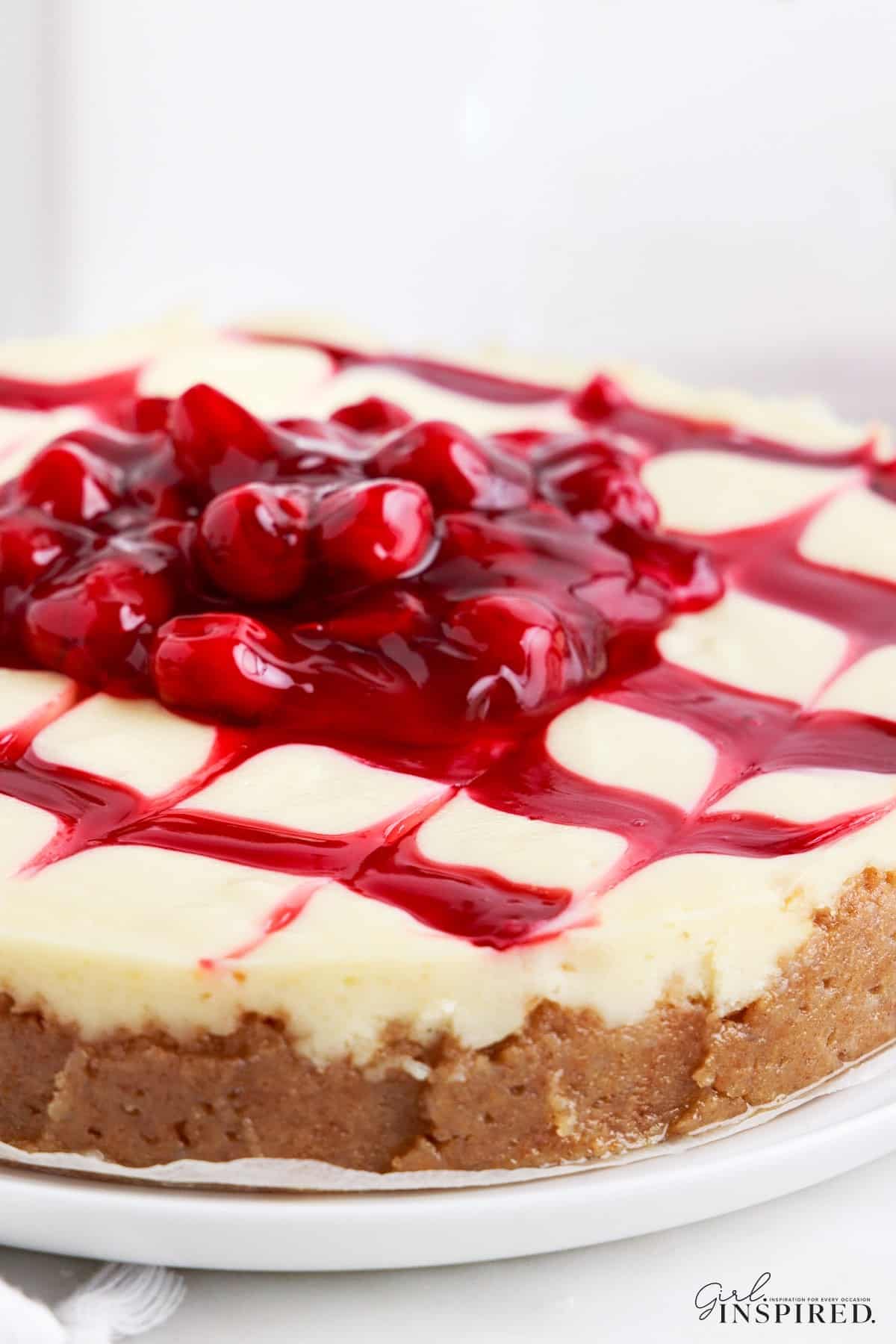 Side view of the Cherry Cheesecake showing the graham cracker crust, cheesecake filling and cherries oozing over the side.