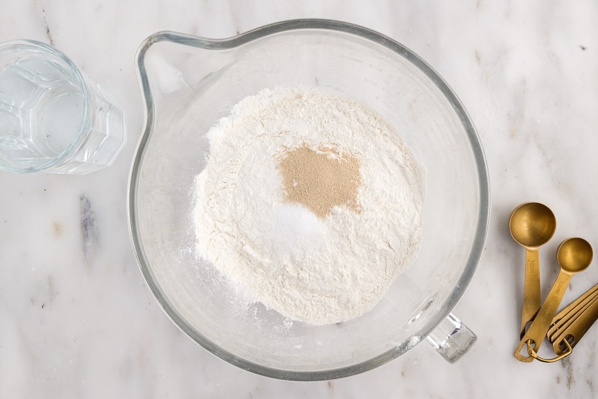 All dry ingredients being mixed in a bowl on the counter., with measuring spoons off to the side.