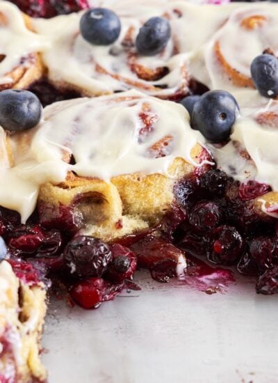 Pan filled with Blueberry Cinnamon Rolls with frosting and fresh blueberries on top.