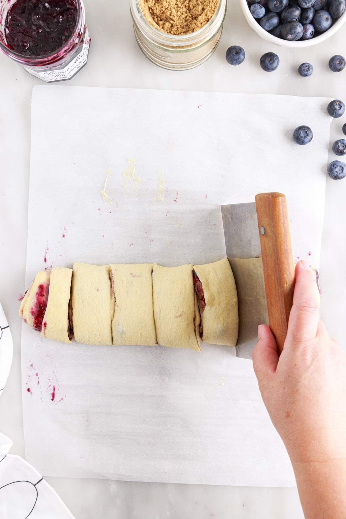 Cutting the rolled dough into similar sized cuts on parchment paper.