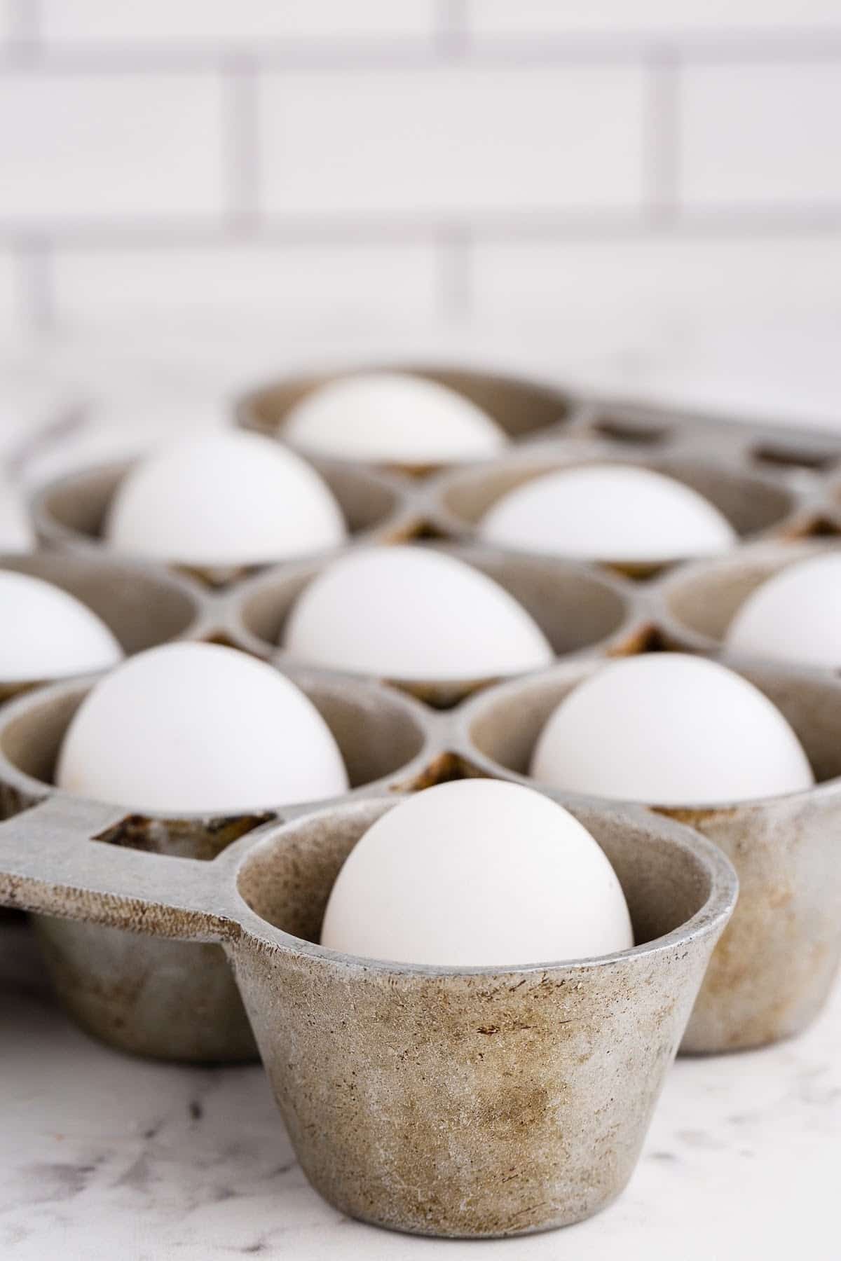 Eggs placed into a muffin tin on the counter.