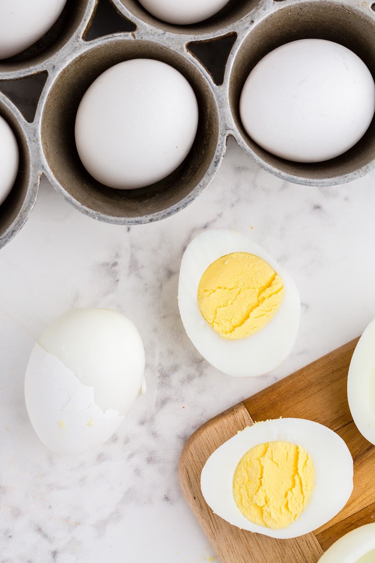 Cut hard-boiled egg on the counter showing the perfectly cooked egg yolk, with other hard-boiled eggs in the background.