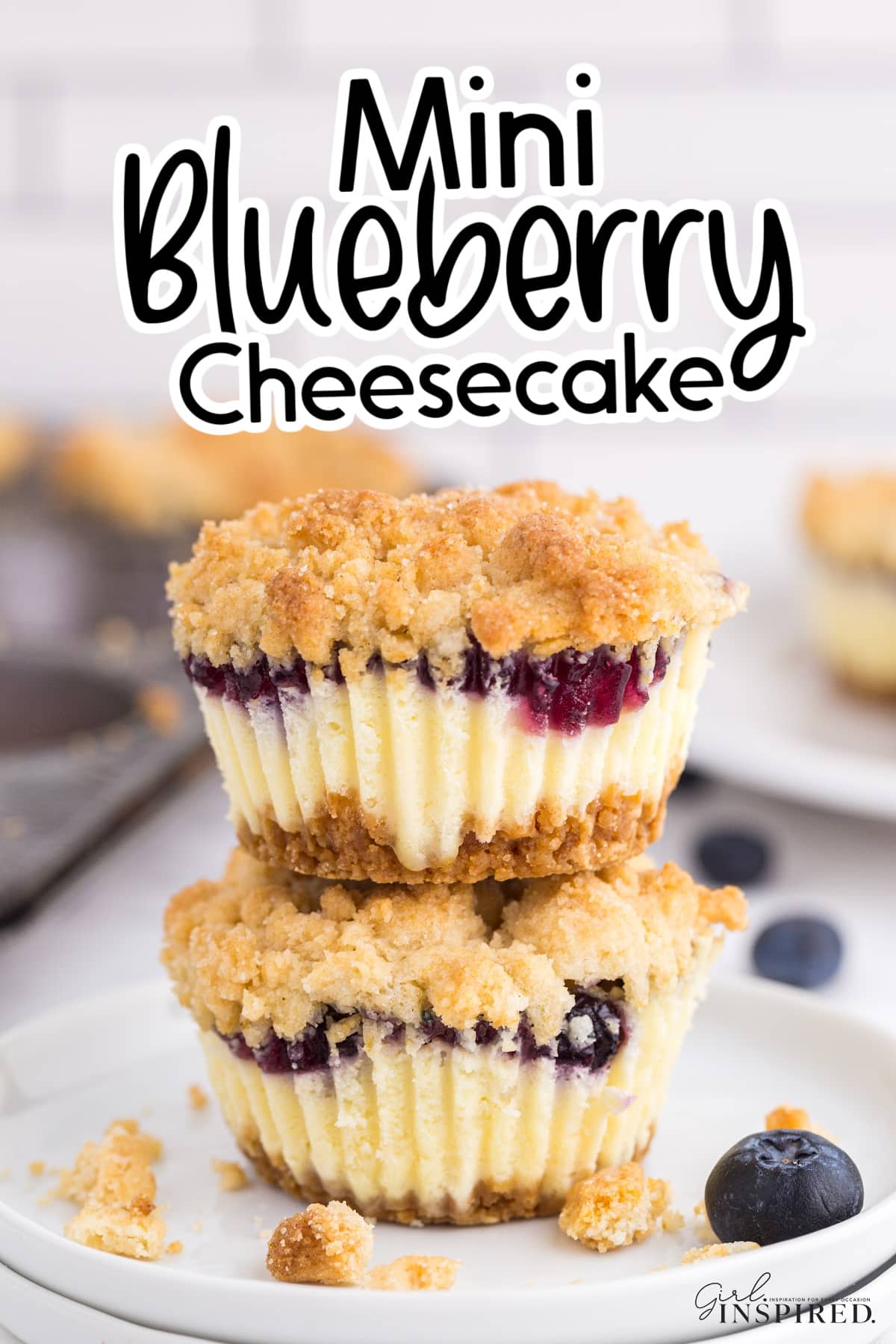 Two stacked Mini Blueberry Cheesecakes on top of one another, with other ingredients in the background and text overlay.