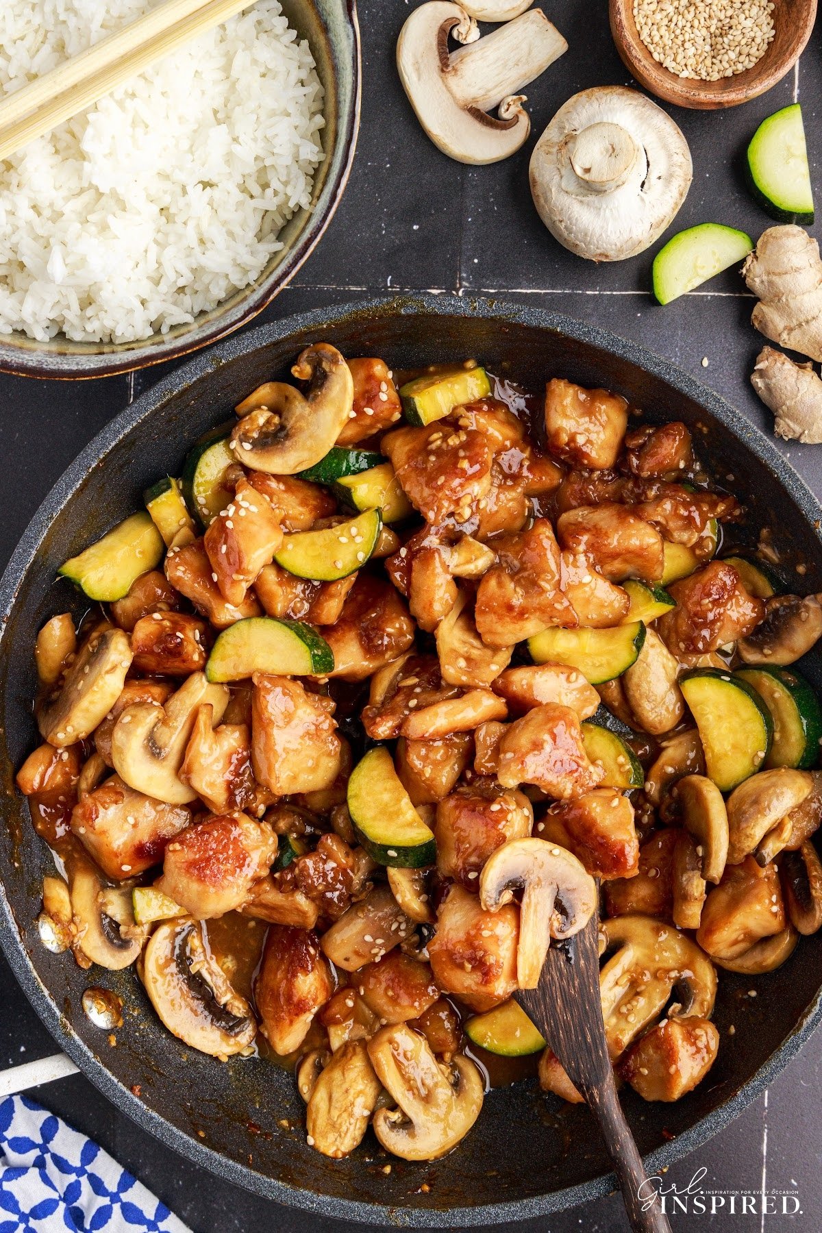 Large skillet of Panda Express Mushroom Chicken, with some scooped on a wooden spoon to show the ingredients, with text overlay.