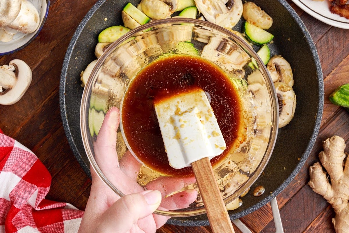 Mixing the sauce for the vegetables in a bowl until well blended, the pan of cut veggies under the sauce bowl.