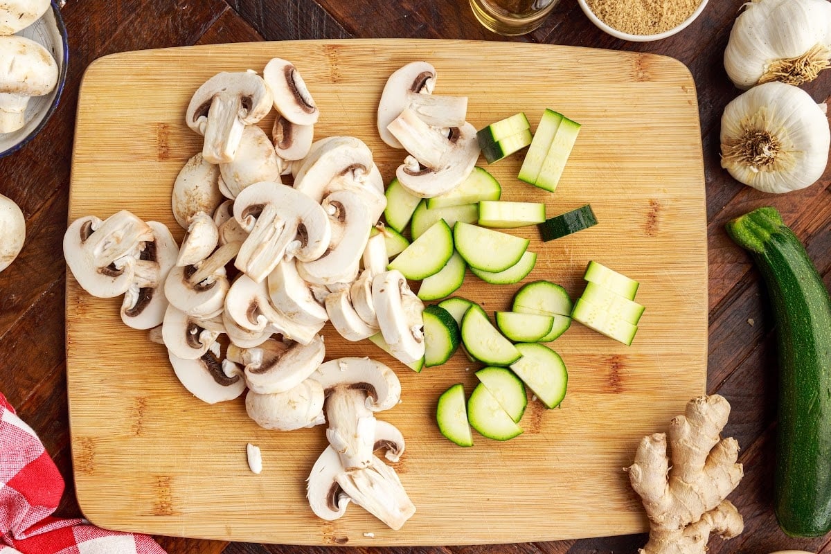 Cutt the veggies on a cutting board. with other ingredients in the background.