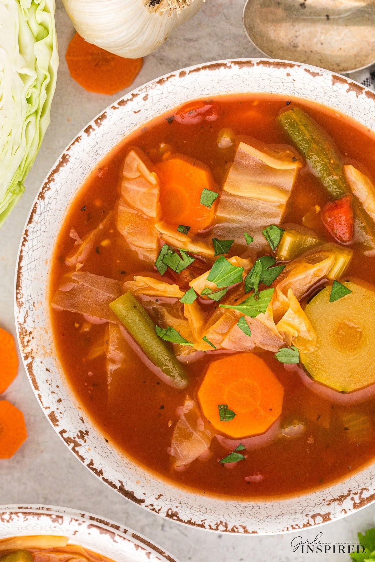 Large bowl of Diet Cabbage soup resting above the pot of soup, showing the ingredients in the photo.