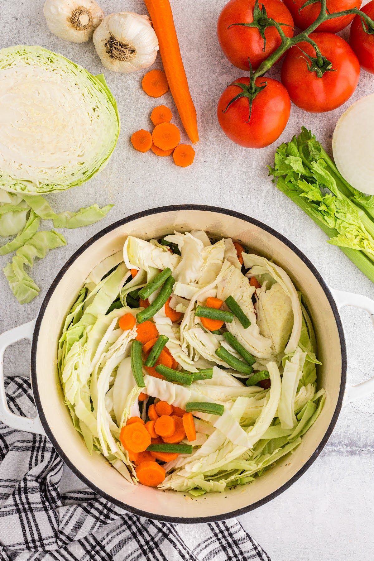 Adding the rest of the fresh veggies to the pot, with other ingredients to make this soup in the background.