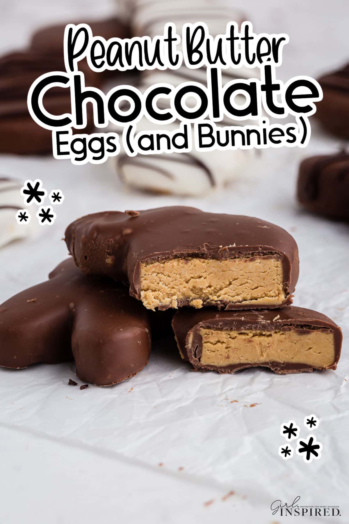 Side view of Peanut Butter and Chocolate Eggs and Bunnies parchment paper on the counter, cut in half showing the inside peanut butter, with other chocolate covered eggs in the background.