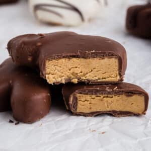 Side view of Peanut Butter and Chocolate Eggs and Bunnies parchment paper on the counter, cut in half showing the inside peanut butter, with other chocolate covered eggs in the background.
