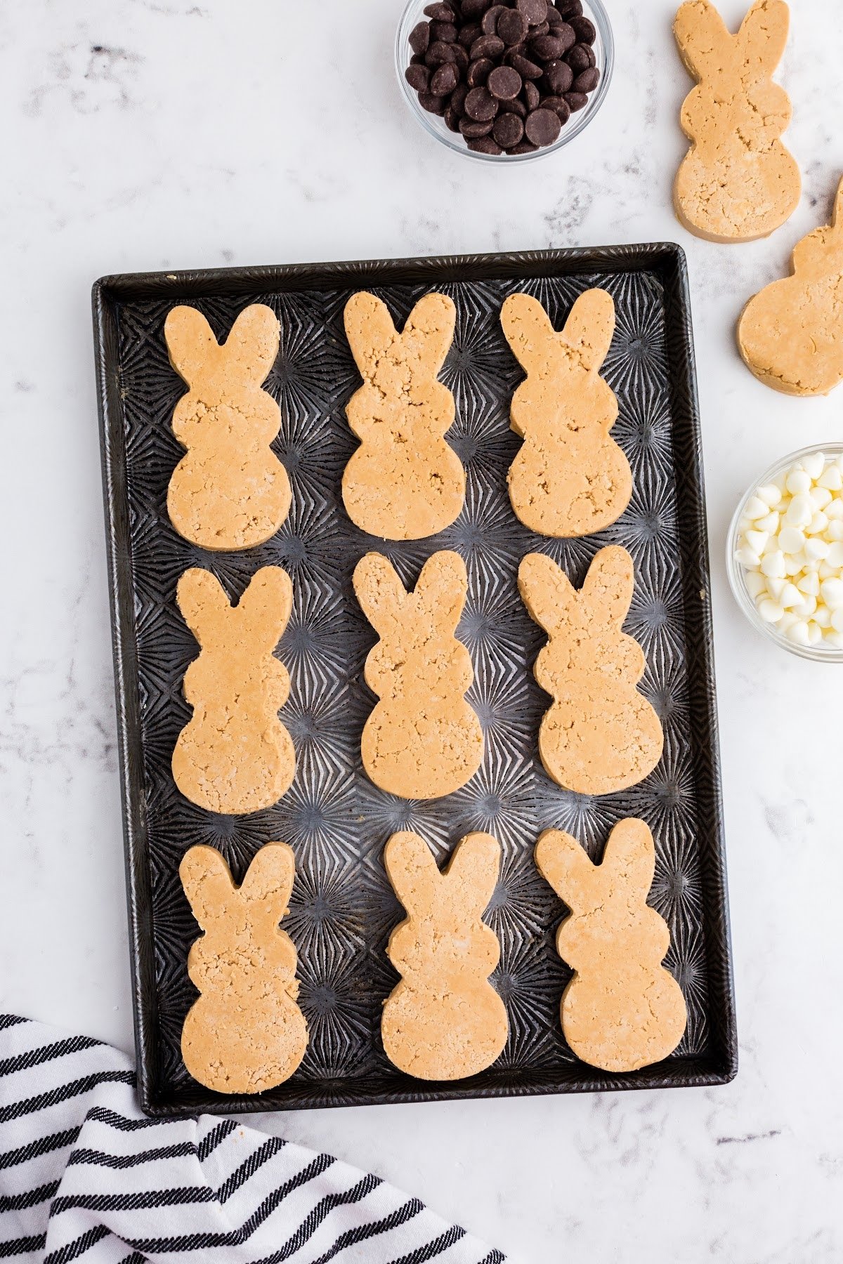 Bunny cutouts of peanut butter are on the baking sheet to be chilled in the freezer.